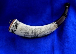 The outside curve of the horn has an engraving of an young Indian who has taken a deer.  His left hand rests on his kill and his right hand holds his rifle.